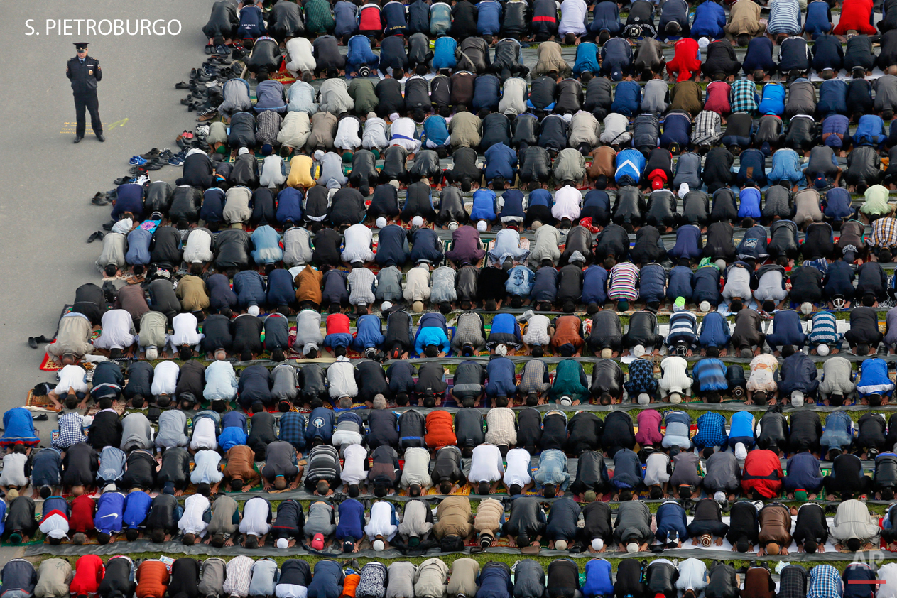 A policeman stands guard as Muslims take part in Eid al-Fitr prayers at a mosque in St. Petersburg, Russia, Friday, July 17, 2015. Millions of Muslims across the world are celebrating the Eid al-Fitr holiday, which marks the end of the month-long fast of Ramadan. (AP Photo/Dmitry Lovetsky)